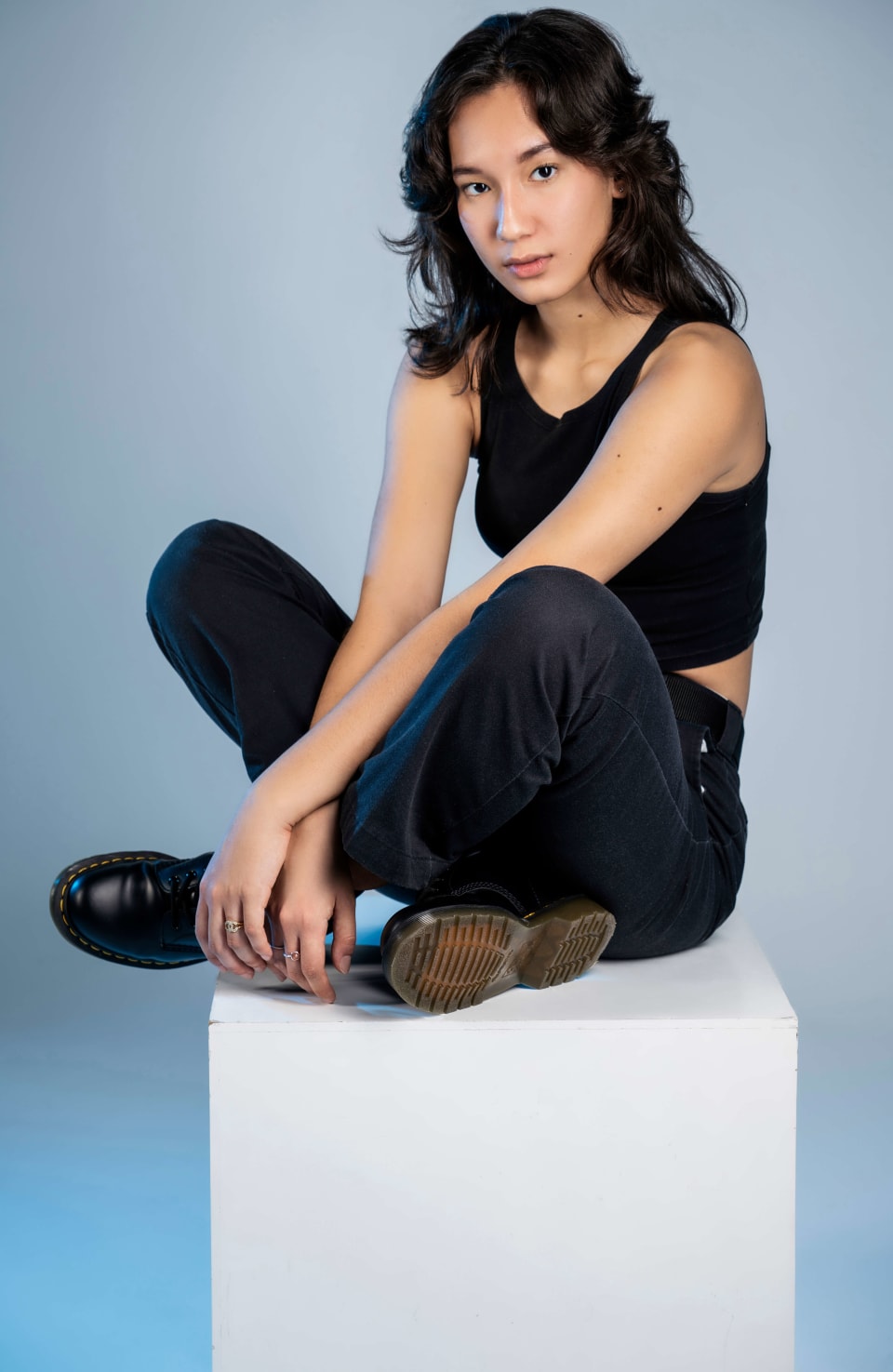 Seated portrait on a white cube, cool blue lighting