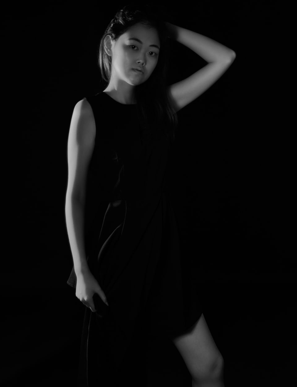 Low-key studio portrait, arm raised, dark backdrop