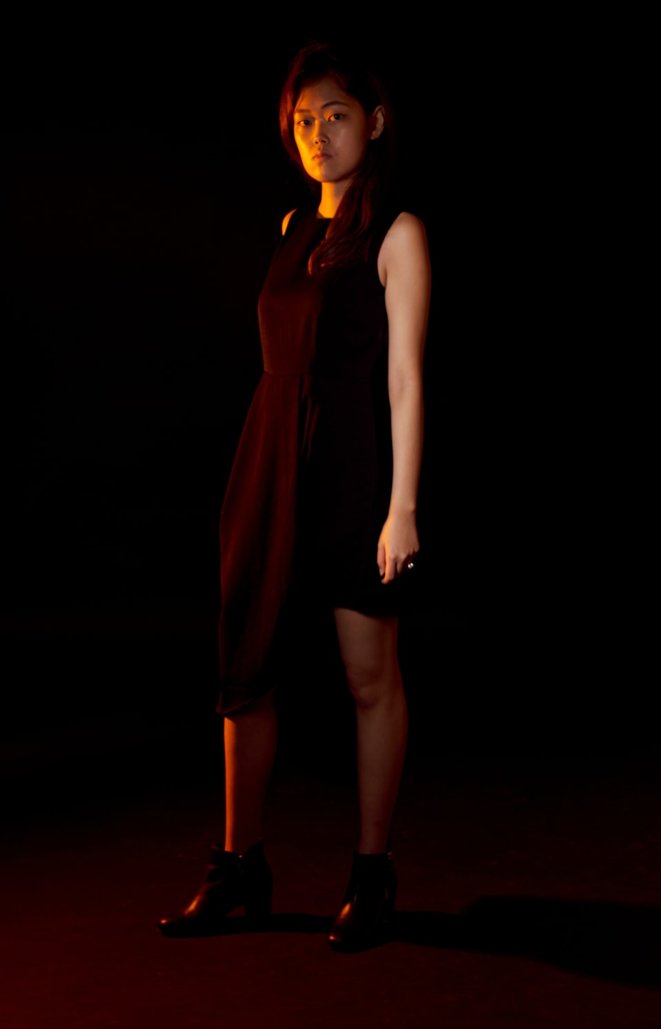 Moody low-key portrait in a deep red dress, direct gaze