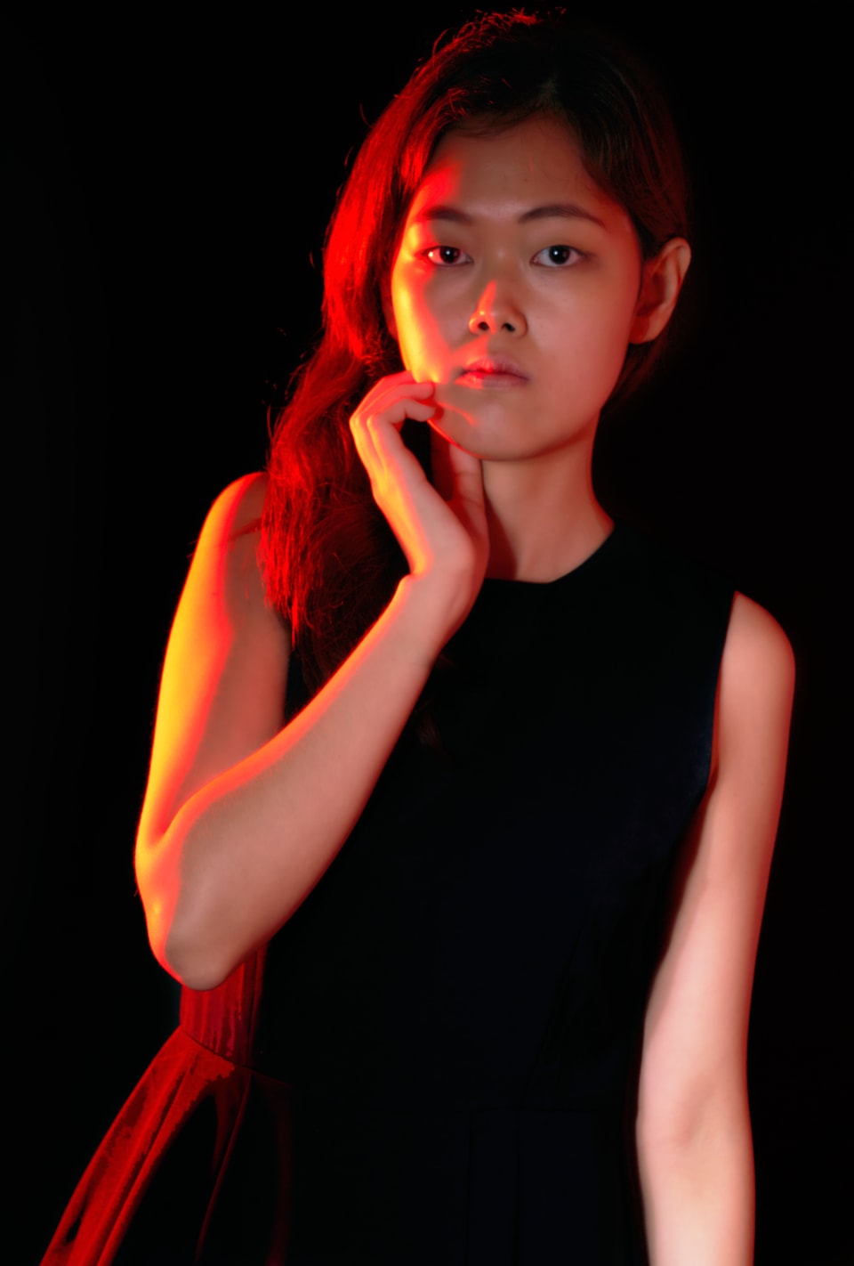 Studio portrait with warm gel lighting, hand at neck