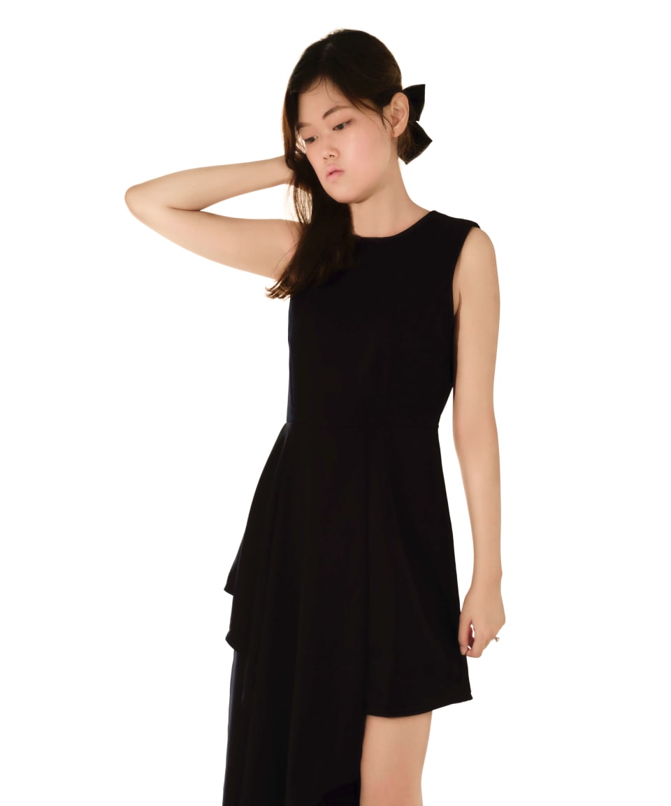 Studio portrait on white background, black dress, arm raised