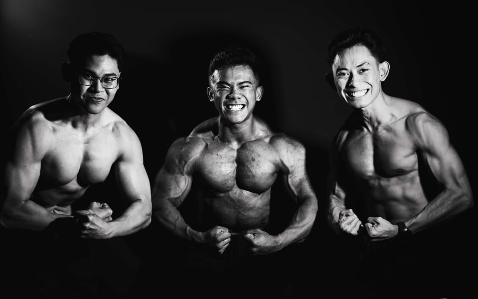 Three gym members flexing together, group portrait