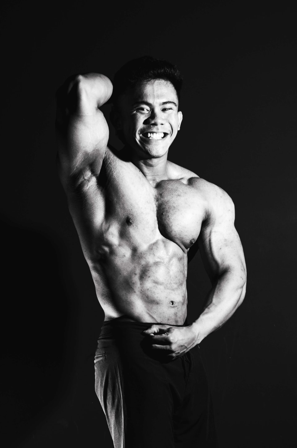 Bicep pose with a raised fist, big smile, black and white
