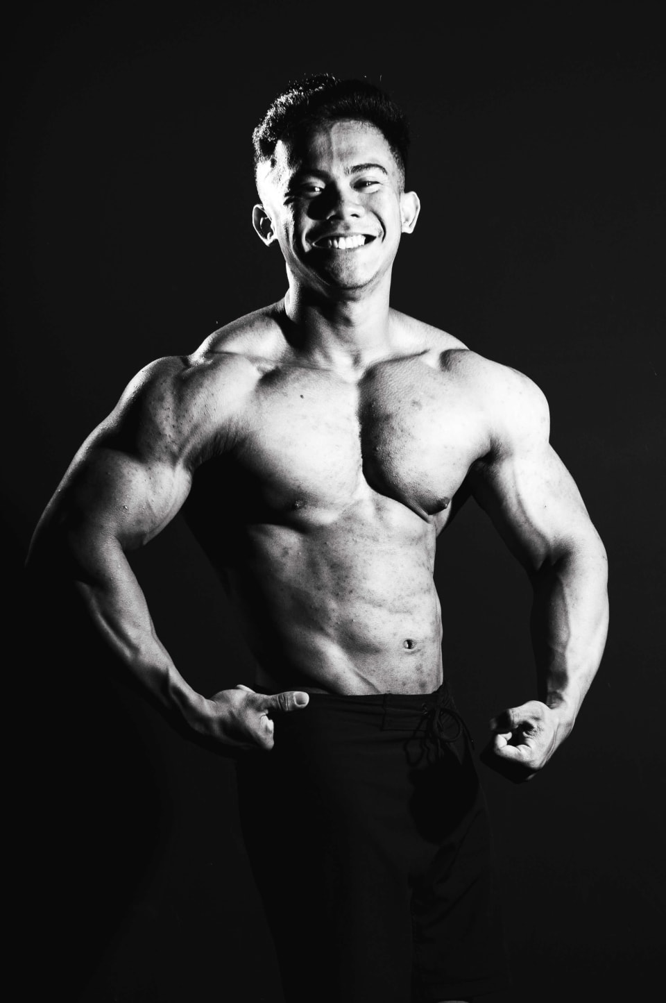 Front double-bicep pose, genuine smile, black and white