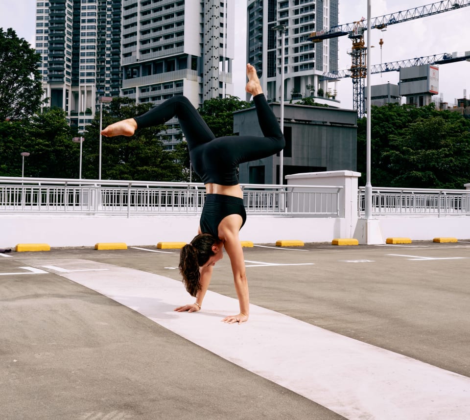 Handstand on a rooftop carpark, city skyline behind