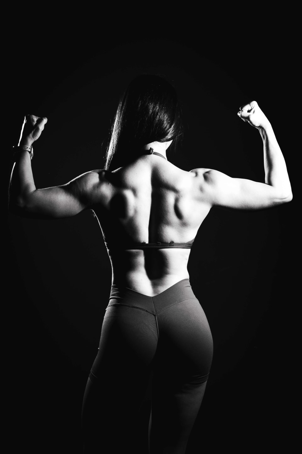 Rear double-bicep pose, back view, dramatic light