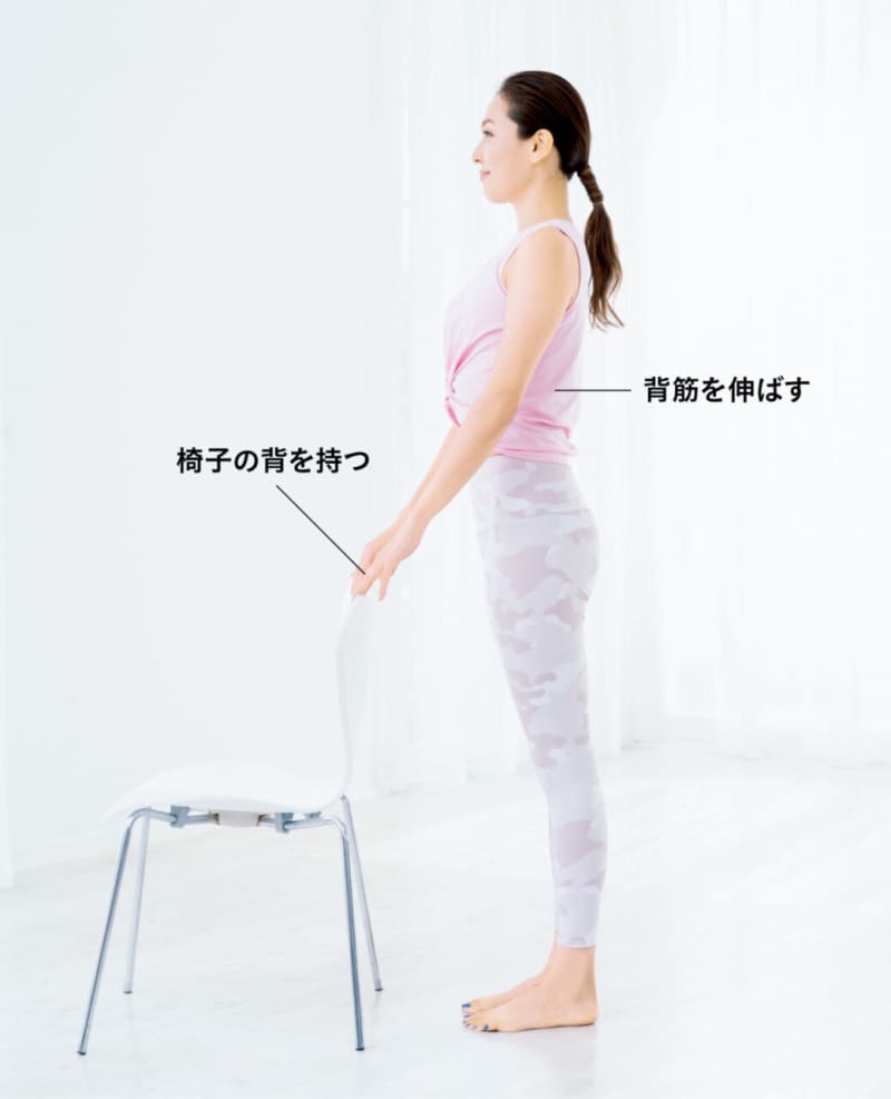 椅子の背を持って立つ