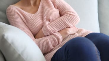 Endométriose journée mondiale 2024 : une femme assise sur un fauteuil entoure son ventre de ses bras.