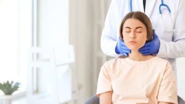 Cancer de la thyroïde : image d'un femme étant auscultée par un médecin , par une palpation de la thyroïde 