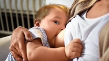 Allaitement maternel : semaine mondiale du 14 au 20 octobre 2024. Image d'un bébé qui tête le sein et regarde en même temps l'objectif.