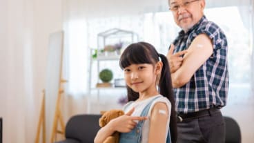 Grippe 2024-2025 : où en est l'épidémie en France ? Image d'un grand-père et de sa petite fille montrant leur bras après avoir reçu le vaccin de la grippe.