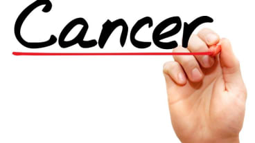 Combien de temps met un cancer pour se développer ? Image qui montre une main en train d'écrire le mot cancer, souligné en rouge.