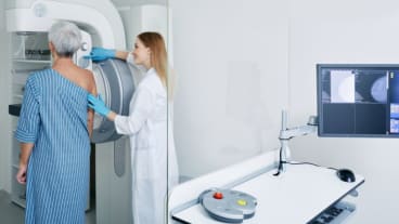 Quels sont les cancers les plus fréquents chez la femme ? Image d'une femme portant une blouse bleue s'apprêtant à passer une mammographie.