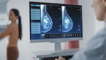 Excellents résultats de l'Enhertu dans le cancer du sein HER2 métastasé. Image d'une femme passant une mammographie et d'un soignant devant son écran de contrôle.