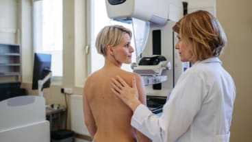 Santé des femmes : améliorer l'accès au dépistage du cancer du sein. Une soignante rassure une patiente torse nu avant de passer une mammographie.