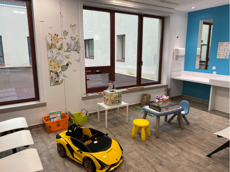 salle d'attente des mineurs dans le service ambulatoire, avec une voiturette électrique, et des jeux pour enfants