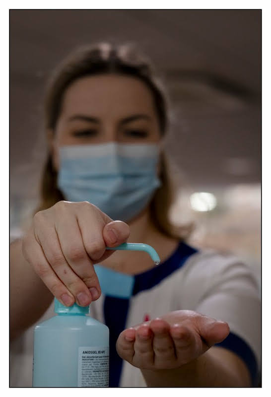 Infirmière qui respecte le protocole sanitaire: se met du gel hydroalcoolique