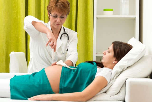 Une soignante pratique un examen d'amniocentèse sur une femme enceinte.