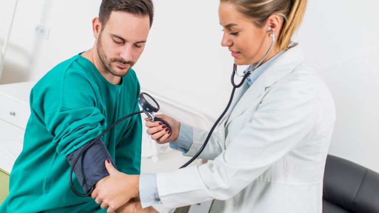Bilan de santé. Elsan Prévention. Une femme médecin prend la tension d'un homme jeune.