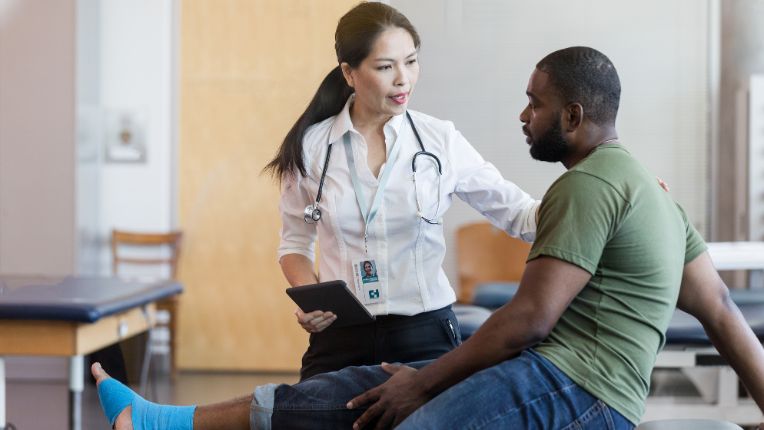 Where to have foot surgery in Marseille when you come from abroad? A caregiver is talking to a patient with a bandaged foot..