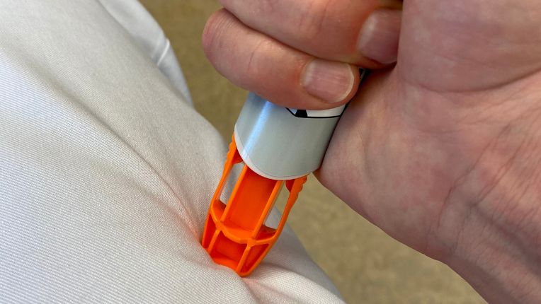 Épinéphrine (adrénaline) : quand l’utiliser, comment l’injecter et effets secondaires. Image d'un stylo injecteur, avec son bout orange, enfoncé dans une cuisse.