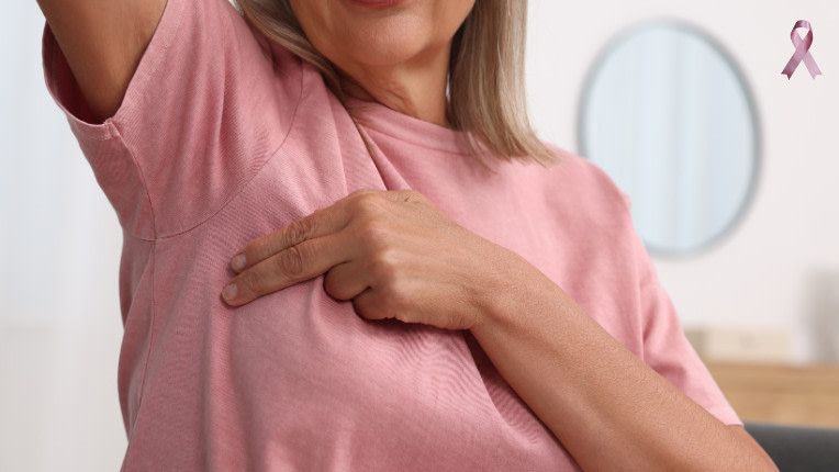 Autopalpation du sein : Une femme passe deux doigts entre son aisselle droite et son sein droit.