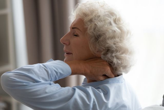 Fibromyalgie : quels symptômes et quelle prise en charge chez ELSAN ? Une femme se tient le haut de l'épaule en grimaçant de douleur.