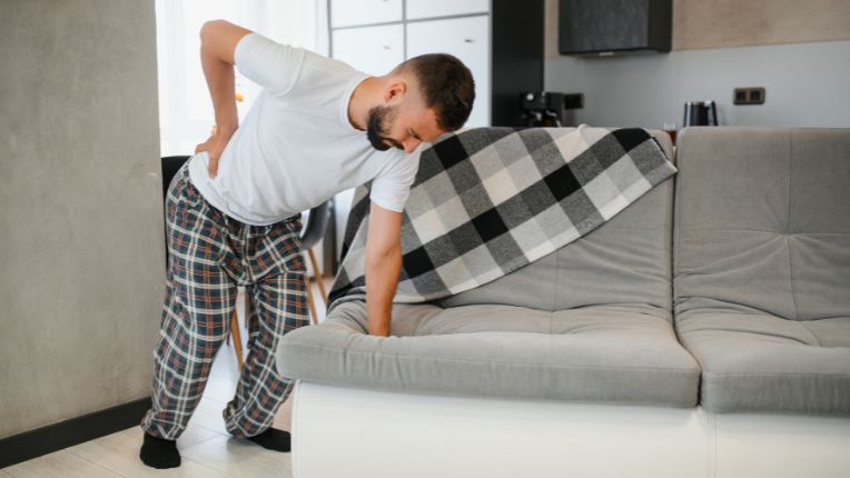 Lumbago : comprendre et soulager la douleur lombaire à l’occasion de la Journée mondiale de la douleur. Image d'un homme penché en deux par une douleur en bas du dos.