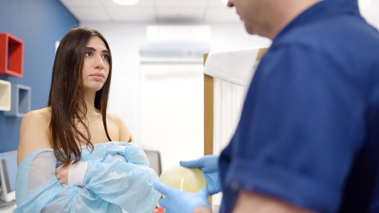 Opération cancer du sein par robot à Brest. Une jeune femme portant une blouse bleue rencontre un soignant qui porte une prothèse mammaire.