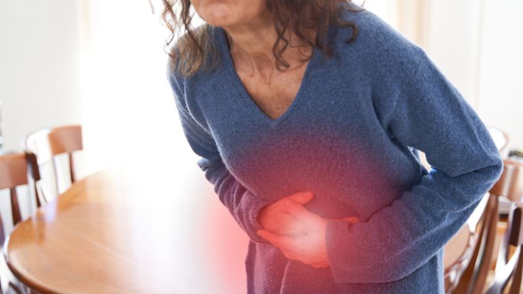 Opération du côlon par robot à Brest. Une femme se tient le ventre de douleur. La douleur est figurée par un halo rouge.