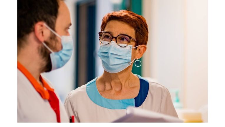 Deuxième avis médical. Patients internationaux ELSAN. Image de deux soignants à l'hôpital qui se transmettent des documents. 