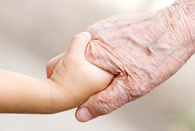 Main d'enfant tenant une main de personne âgée. La progéria ou syndrome de Hutchinson-Gilford est une maladie génétique rare caractérisée par un vieillissement prématuré.