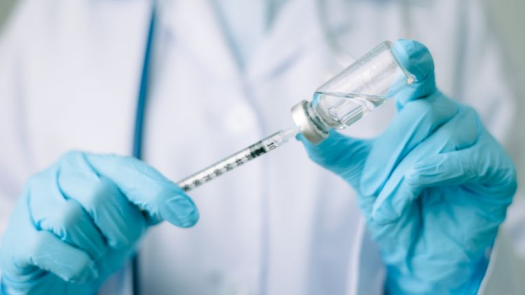 Vous habitez Lyon, ou ses alentours, comme Saint-Etienne, notamment, vous préparez un voyage à l’étranger ? Le vaccin contre la fièvre jaune est obligatoire pour certaines destinations. Image d'un soignant en train de remplir une seringue avec une fiole de vaccin.