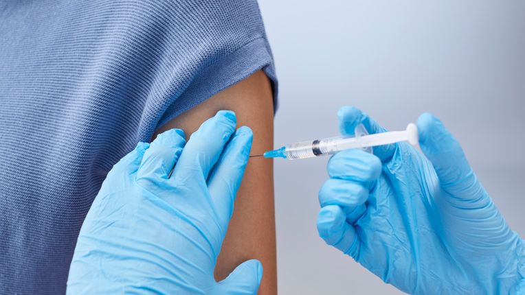 Vaccin fièvre jaune Paris. Image de mains gantées de soignant qui est en train de pousser sur une seringue, injectant un vaccin dans le bras d'une personne.