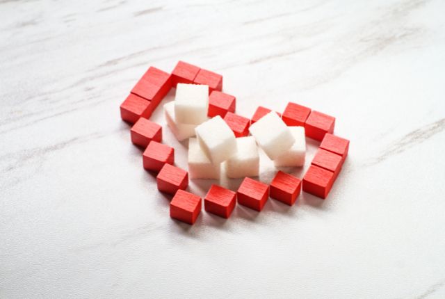 Diabète de type 2 : un coeur est figuré avec des cubes rouges entourant des carrés de sucre blanc.