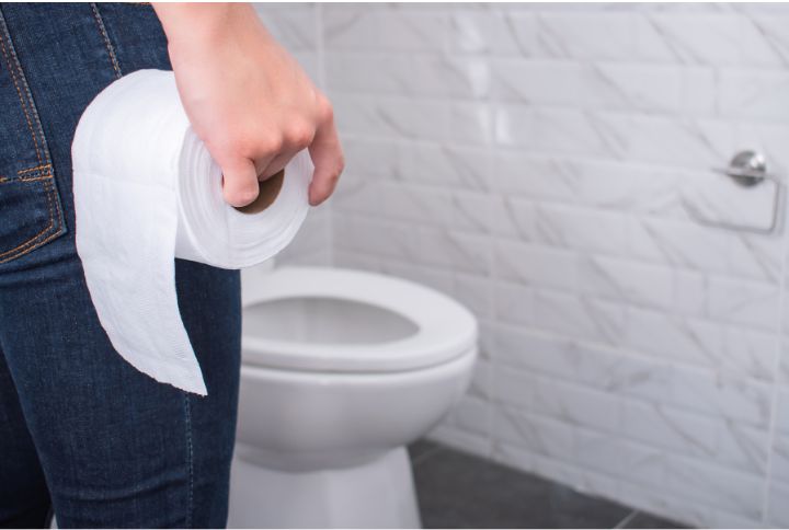 Glaire dans les selles : image d'une personne de dos avec un rouleau de papier devant un wc..