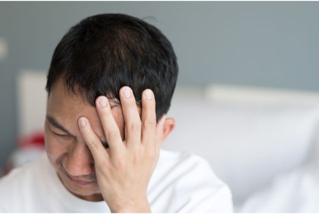 Encéphalite : un homme se tient la tête de douleur...