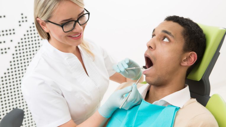 Muguet buccal : une dentiste contrôle la bouche d'un patient.