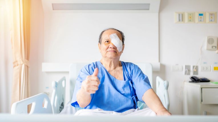 Opération de la cataracte pour les personnes provenant d'un pays étranger : un patient lève le pouce assis sur son lit.