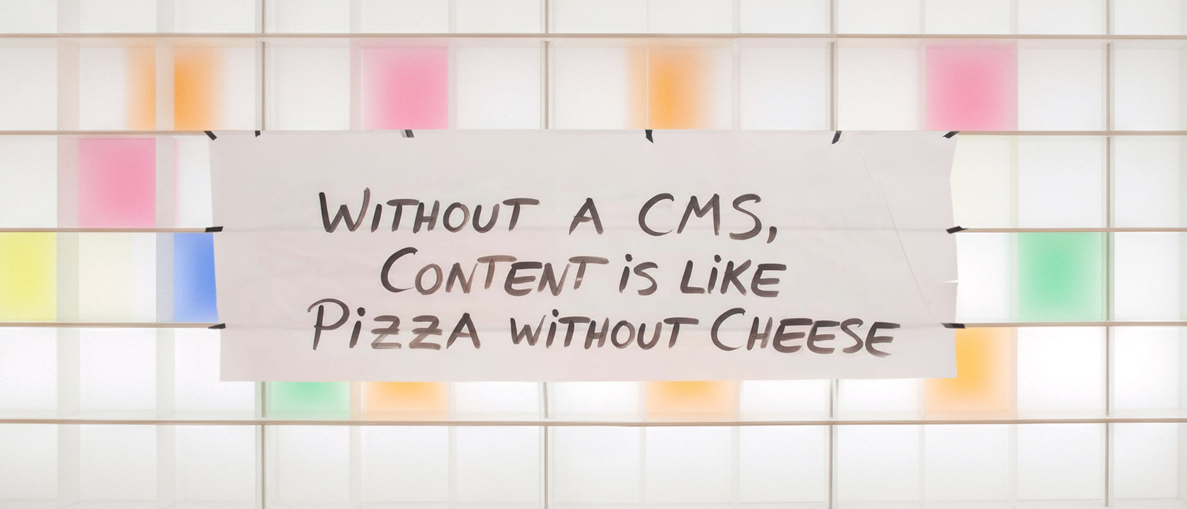 A white shelf with colorful compartments. A piece of paper hangs on the shelf with a saying: Without CMS, content is like pizza without cheese.