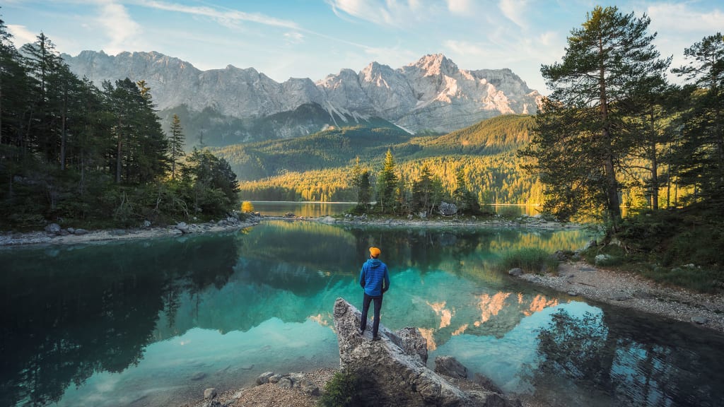 Mann vor einem Bergsee, der in die Berge blickt