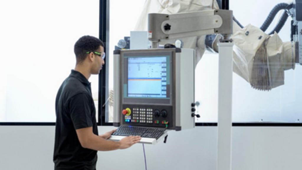 Arbeiter der einen Roboterarm bedient.png