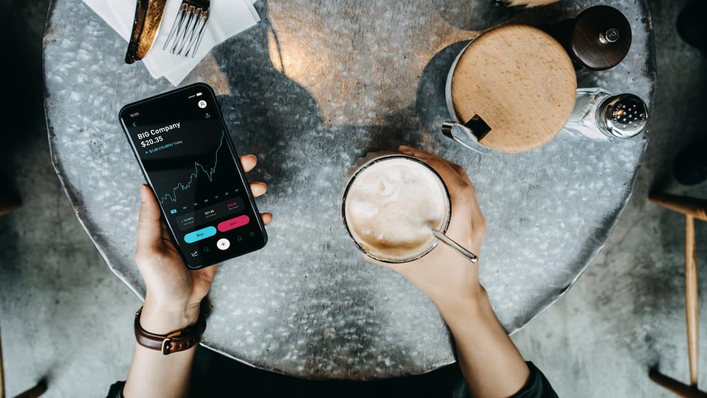 Vogelperspektive, Kaffee auf dem Tisch und Person hält das Handy in der Hand