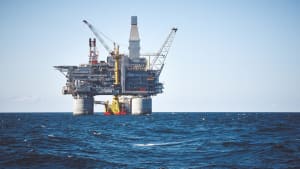 Olieplatform og støtteskib i offshore-område. Blå klar himmel, hav