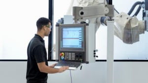 Arbeiter der einen Roboterarm bedient.png