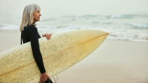 Dame mit Surfbrett - Titelbild Derinews - Longevity