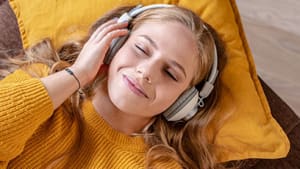 Frau mit Kopfhörern entspannt auf Sofa