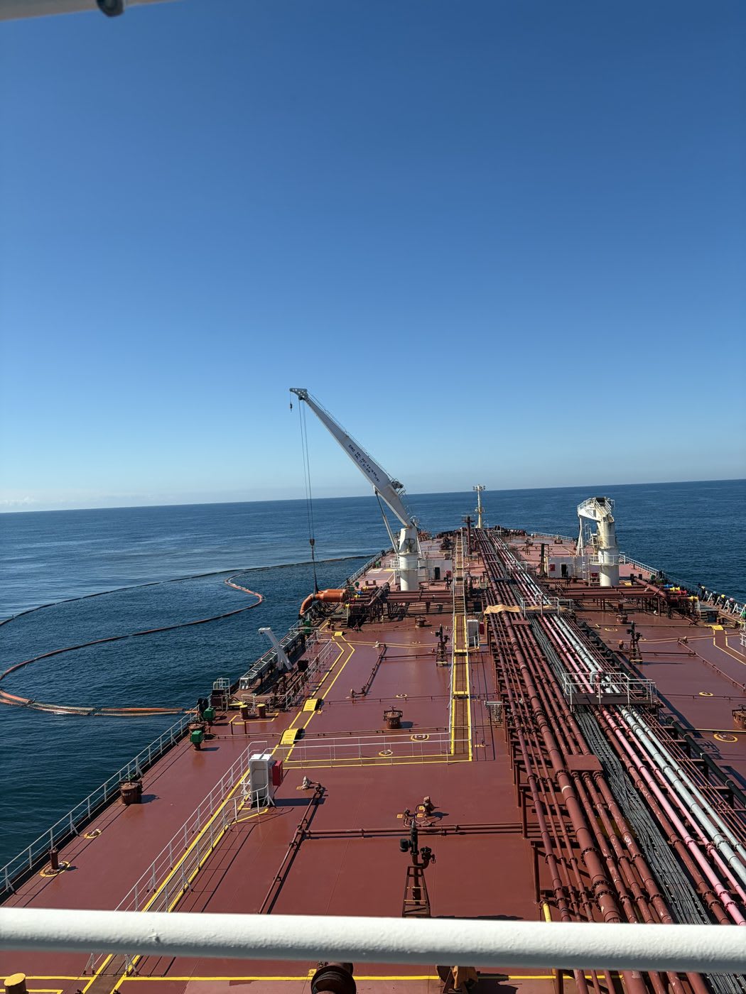 Convés de navio-tanque com barreira de contenção laranja no mar