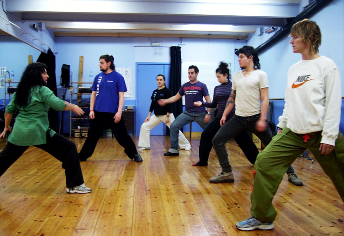 Plano general de una clase de movimiento con ocho alumnos en una sala con parquet