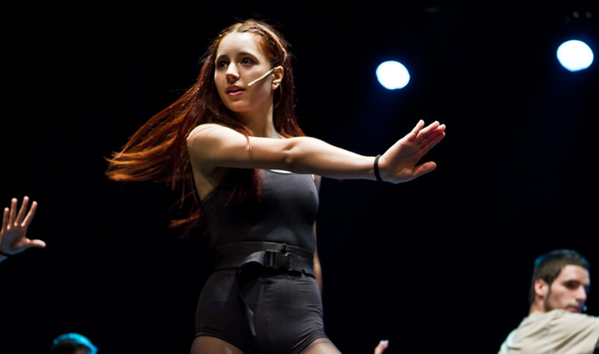 Intèrpret amb micro de diadema i el cabell en moviment durant una coreografia